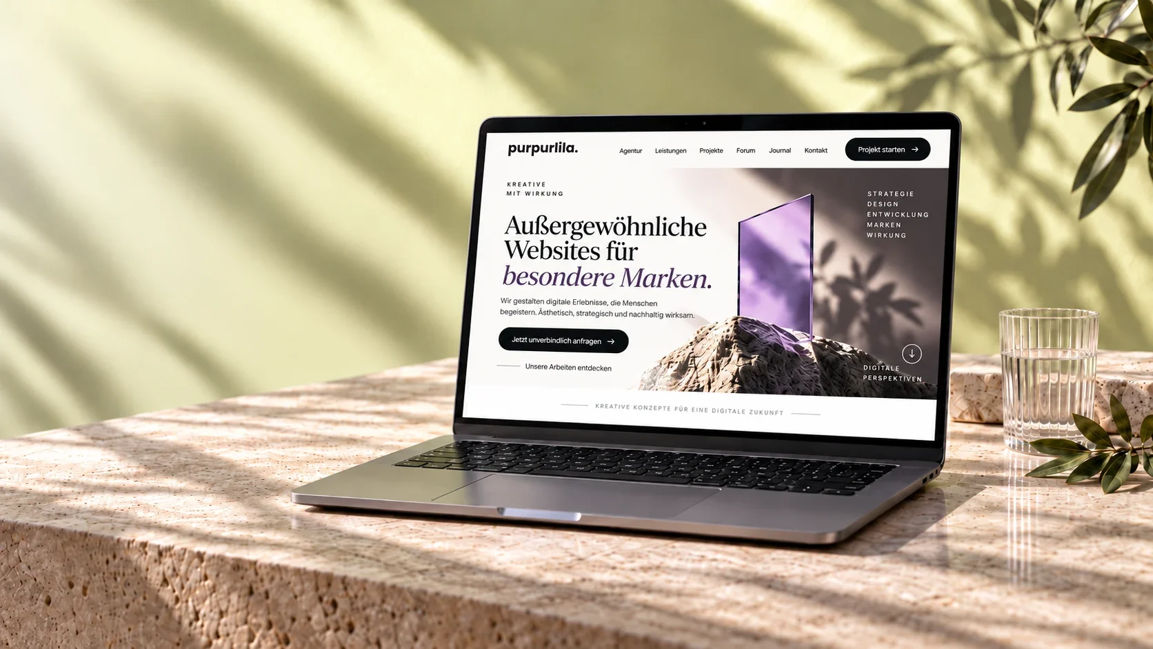 Fiktive Webdesign-Studie: Laptop mit einer purpurlila-Website auf hellem Naturstein.