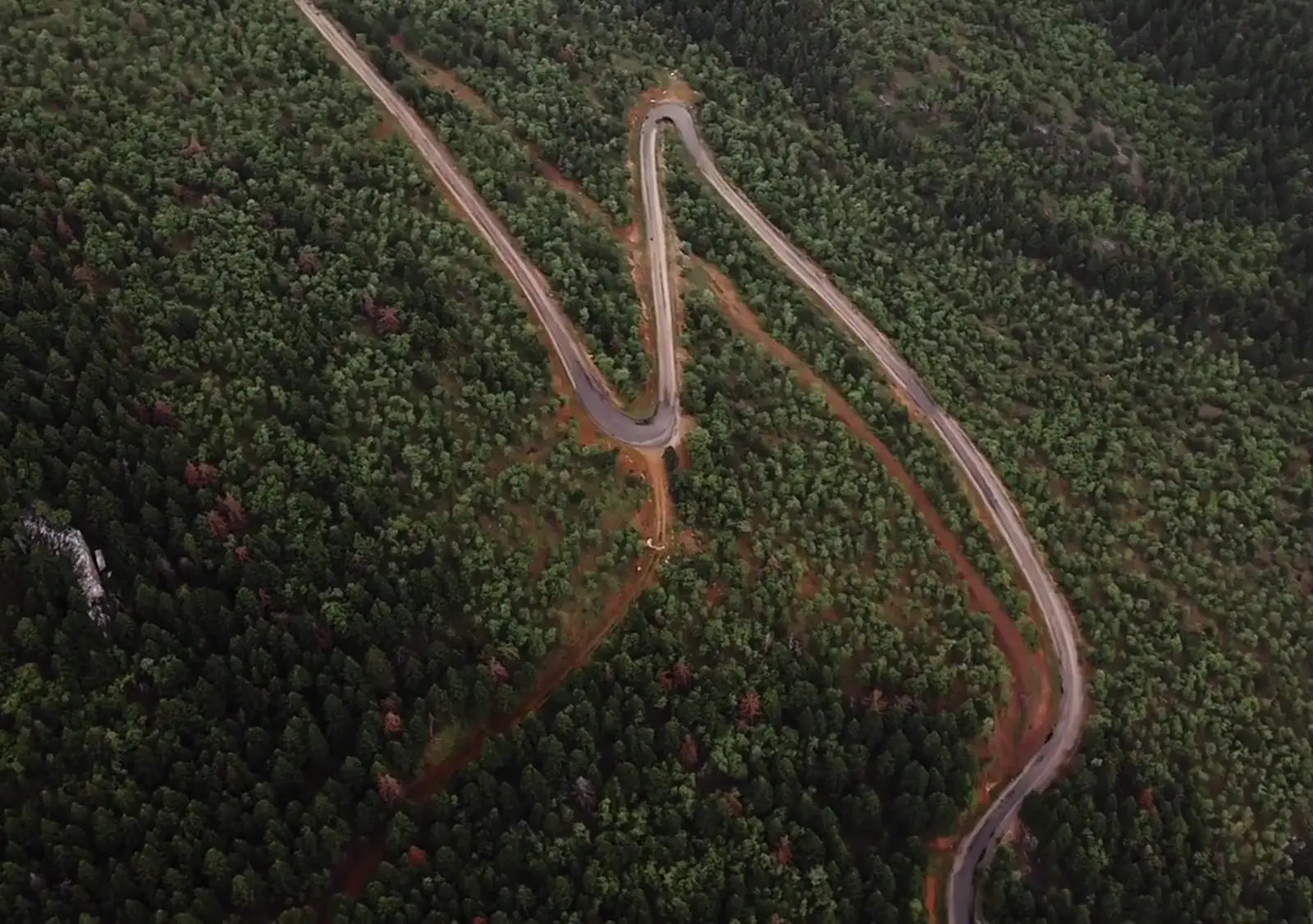 Standbild der kurvigen Straße zwischen bewaldeten Bergen